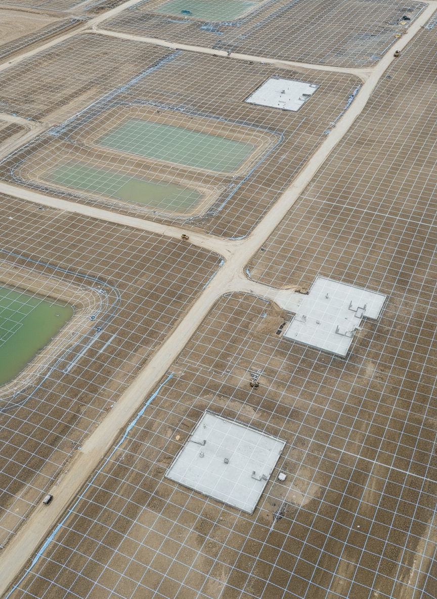 A precise 3D digital terrain model visualization of a construction site, rendered in photographic style, with a grid overlay and subtle contour lines draped across graded earth, retention ponds, and access roads. The view is taken from an elevated oblique angle, showing both height variations and planimetric detail. Soft, even overcast lighting minimizes harsh contrast, letting the subtle earth tones, gravel textures, and newly poured concrete pads remain clearly defined. The mood is technical, analytical, and highly professional, suggesting engineering-grade deliverables. The composition uses asymmetrical balance, with the main elevation changes drawing the eye, evoking a modern, data-focused client report illustration.